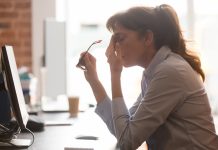 Tired female employee suffer from headache at workplace with long covid brain fog