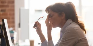 Tired female employee suffer from headache at workplace with long covid brain fog