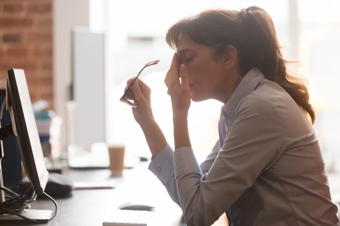 Tired female employee suffer from headache at workplace with long covid brain fog