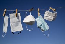 Various types of Covid masks hanging to dry/air out on washing line against a clear blue sky