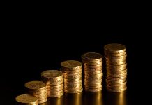 Black background with stack of British pound coins in varying amounts