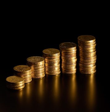 Black background with stack of British pound coins in varying amounts