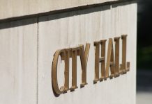 Sign on wall in gold lettering reading 'CITY HALL'