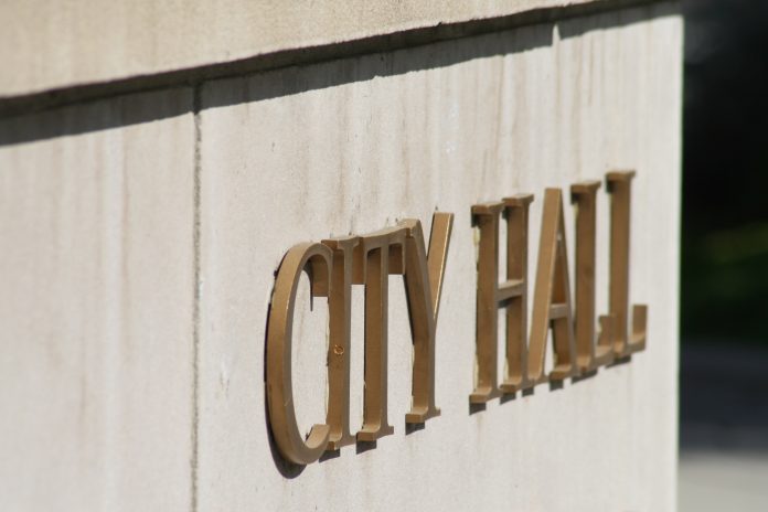 Sign on wall in gold lettering reading 'CITY HALL'