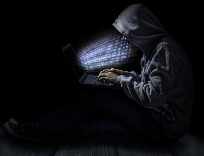 Man in dark room suggestive of cyber attack