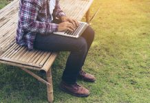 Man working on laptop sat outside in rural area