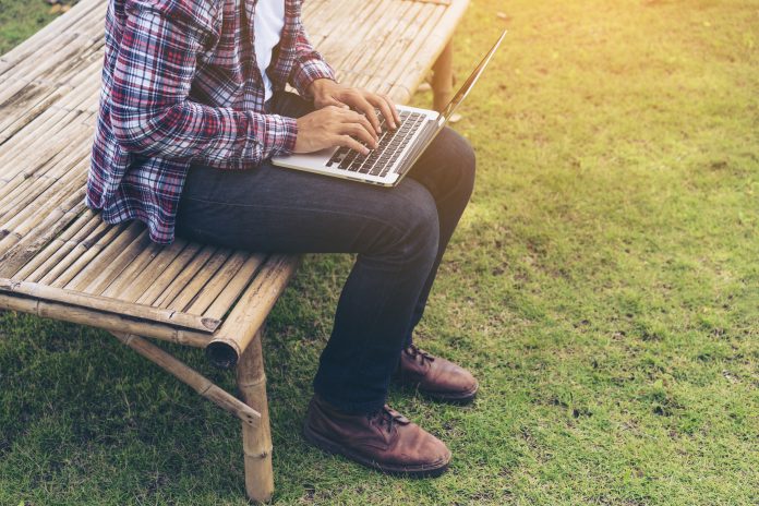 Man working on laptop sat outside in rural area