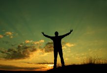 Silhouette of man with hands in air against a beautiful sunrise/sunset