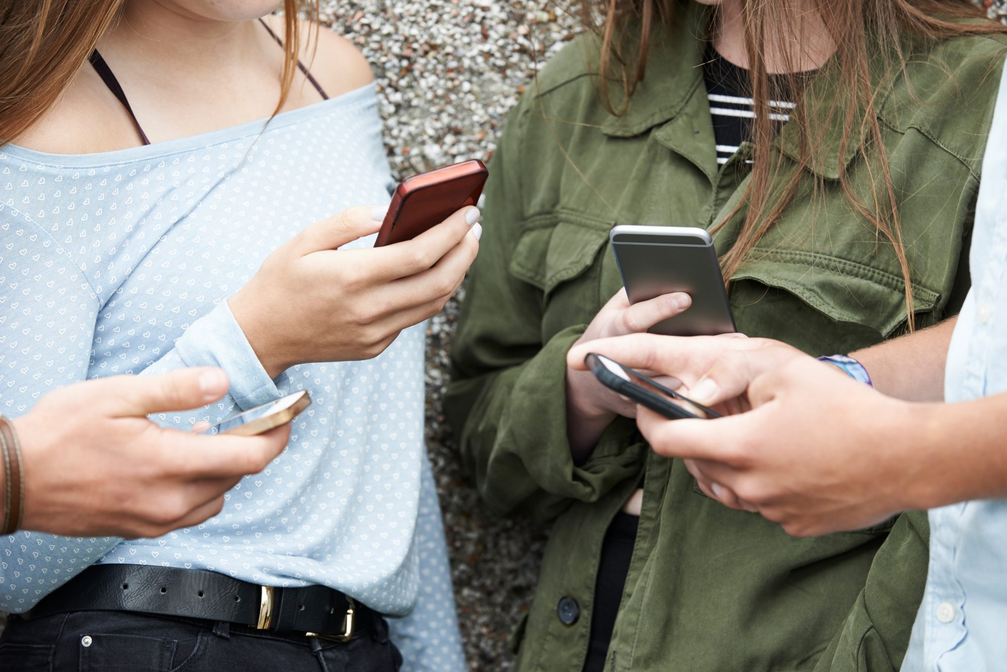 Group of teenagers socialising, looking on their phones