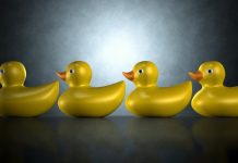 Four yellow rubber ducks sitting in a row against a dark blue green background