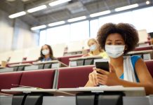 Student girl in mask with smartphone at lecture, recruitment