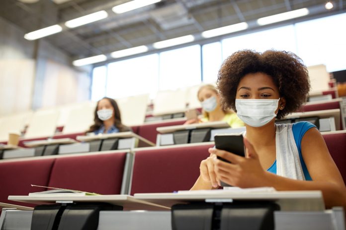 Student girl in mask with smartphone at lecture, recruitment