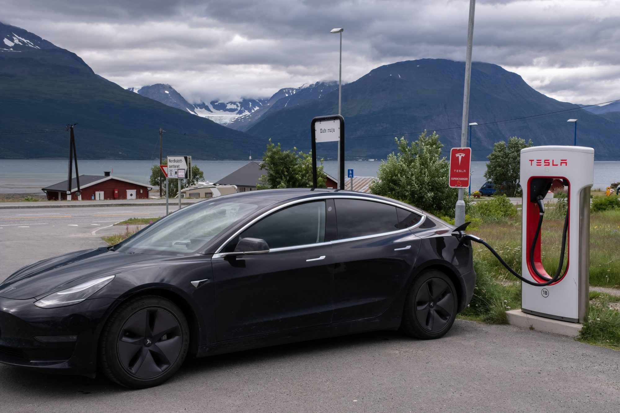 A static shot of a solid black Tesla Model 3 dual motor charging at the Skibotn Supercharger