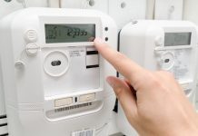 Person pressing button on white electric energy meter