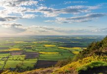 View from the Wrekin, near Telford, Shropshire, England, UK - looking northwest towards Leaton. Patchwork fields of green, yellow under cloudy blue sky