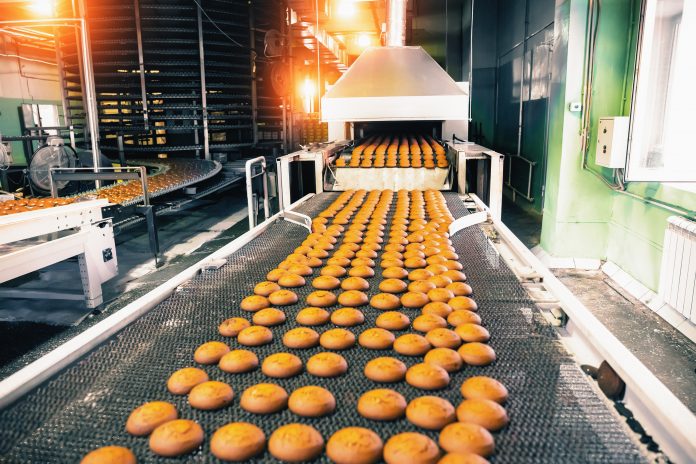 Bakery production line with sweet cookies on conveyor belt in confectionery factory workshop, food production manufacturing