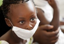 wearing a surgical mask, awaiting treatment for her mother for tuberculosis at a local clinic.