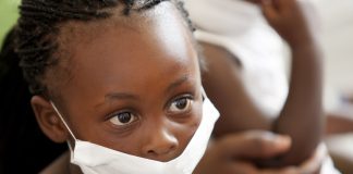 wearing a surgical mask, awaiting treatment for her mother for tuberculosis at a local clinic.