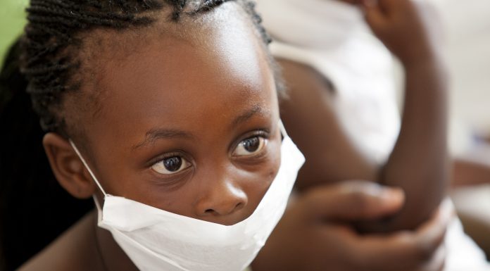 wearing a surgical mask, awaiting treatment for her mother for tuberculosis at a local clinic.