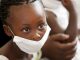 wearing a surgical mask, awaiting treatment for her mother for tuberculosis at a local clinic.