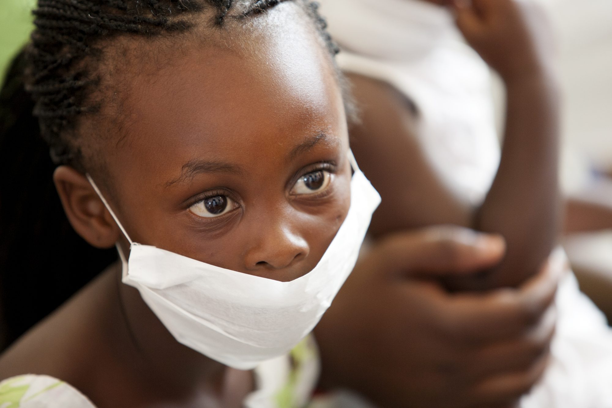 wearing a surgical mask, awaiting treatment for her mother for tuberculosis at a local clinic.