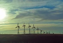 Wind turbines lined up against a cloudy sky