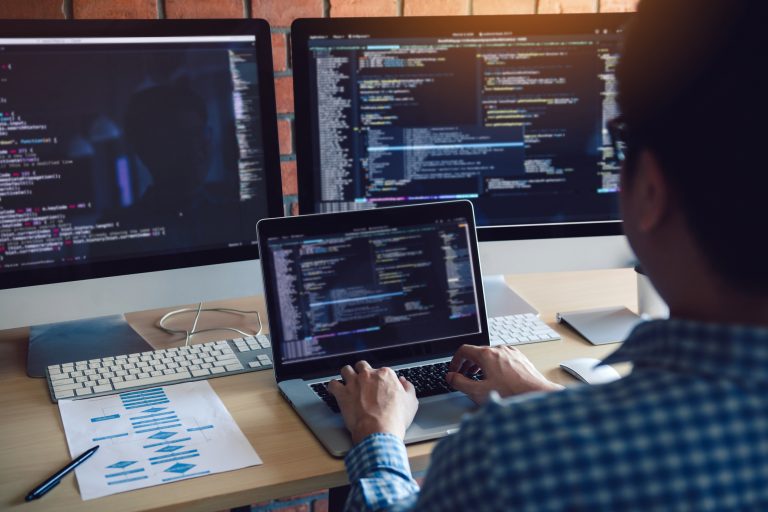 Rear view of software developers is sitting serious analyzing data on the computer screen