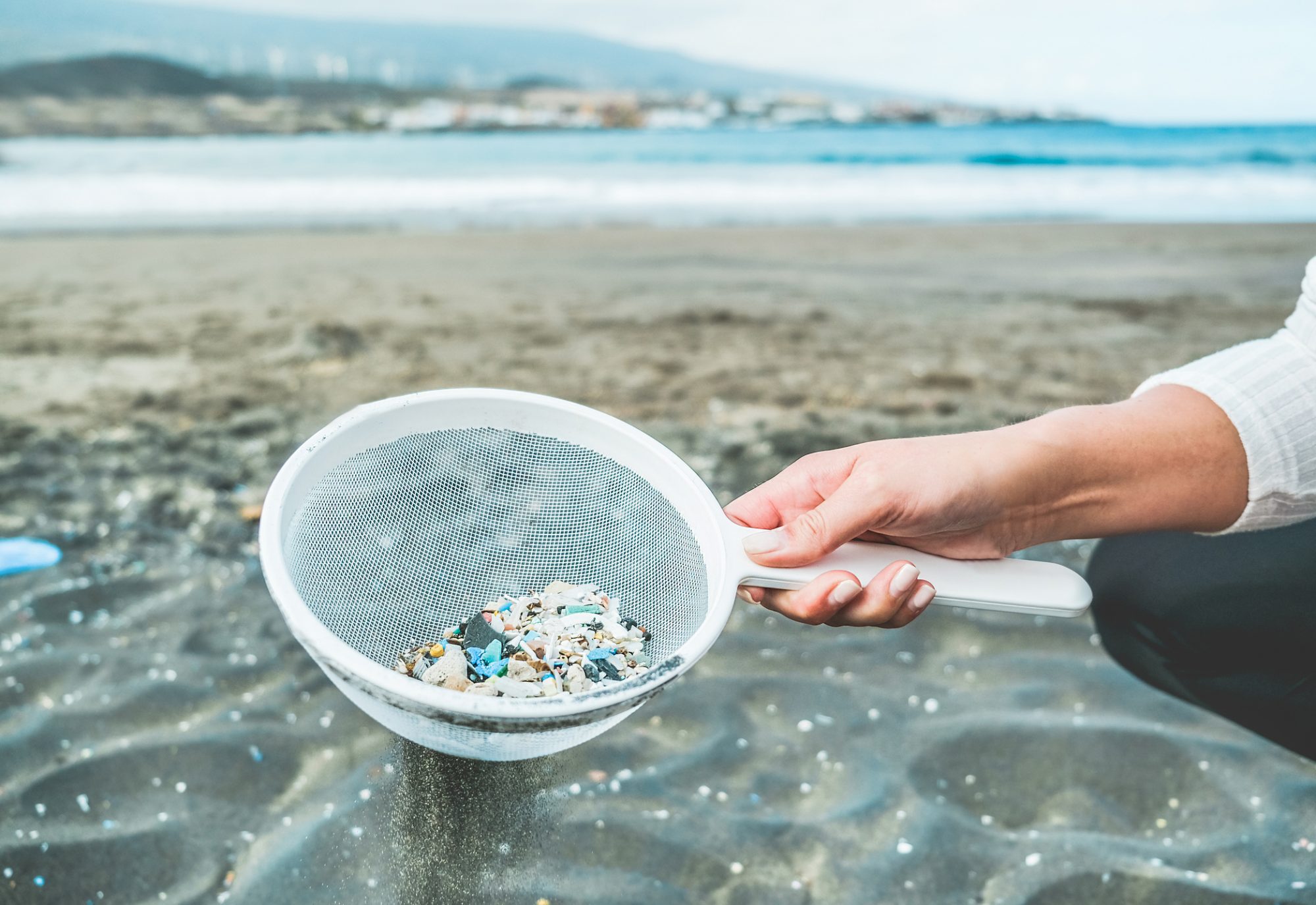 Young woman cleaning microplastics from sand