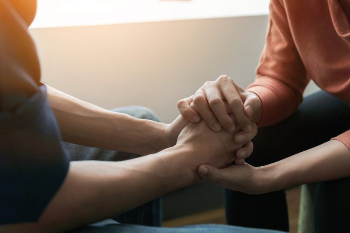 Mental health concept, Psychologist sitting and touch hand young depressed man for encouragement