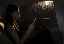 Young woman sitting in the car and texting on her phone on a rainy night in Beijing