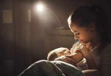 Breastfeeding. mother feeding baby breast in bed dark night