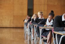 Teenage students In uniform sitting examination in school hall