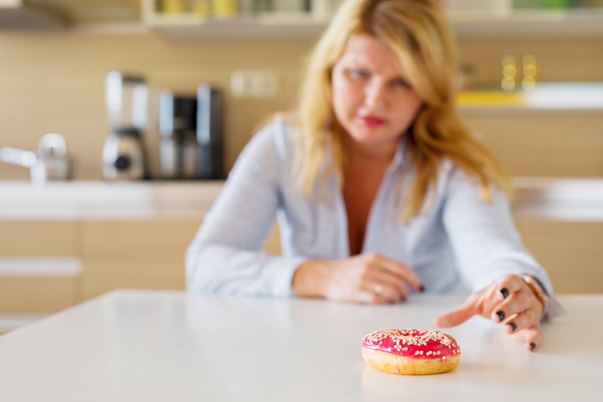 Woman reaching for doughnut, having to battle sugar cravings