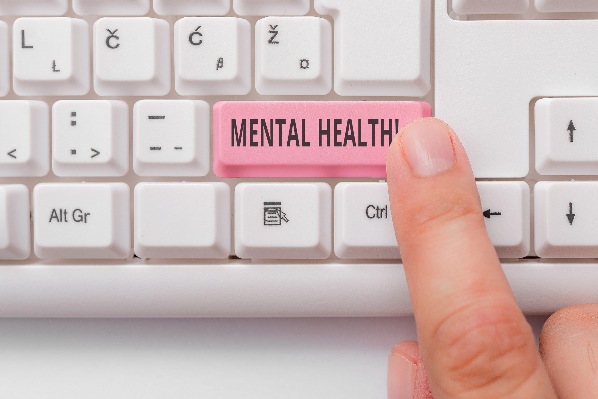 White computer keyboard with person's finger pointing to pink 'MENTAL HEALTH' button