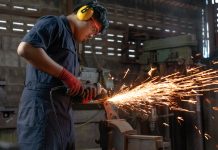 Engineer operating angle grinder hand tools in manufacturing