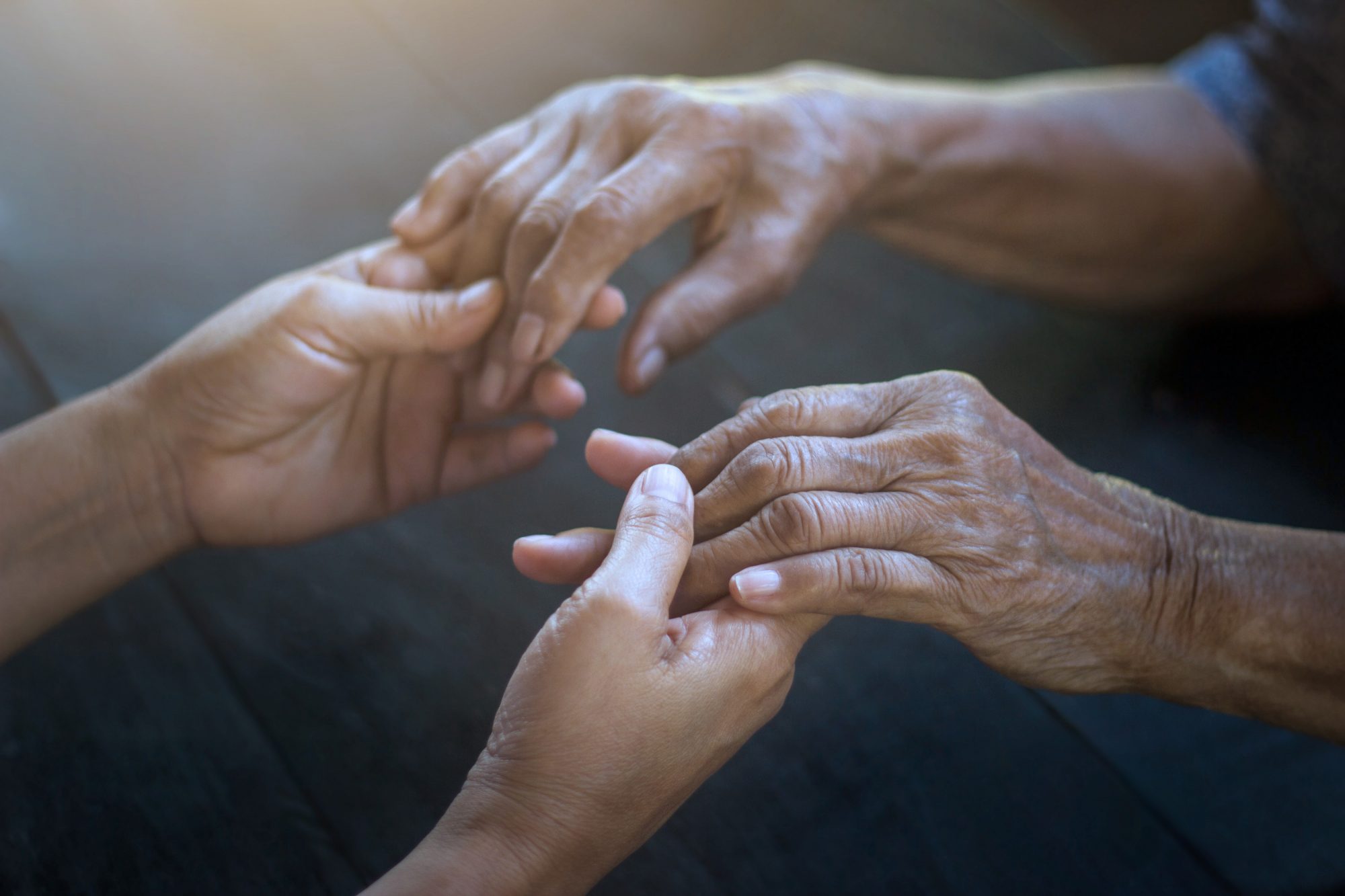 Nurse holding elderly patient's hands 