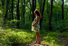 Pregnant woman posing with her bump in lush green forest