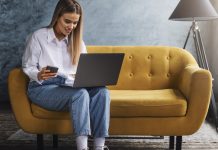Woman learning new digital skills on laptop, sat on yellow couch