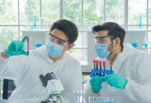 Two scientists wearing masks working in lab inspecting test tubes