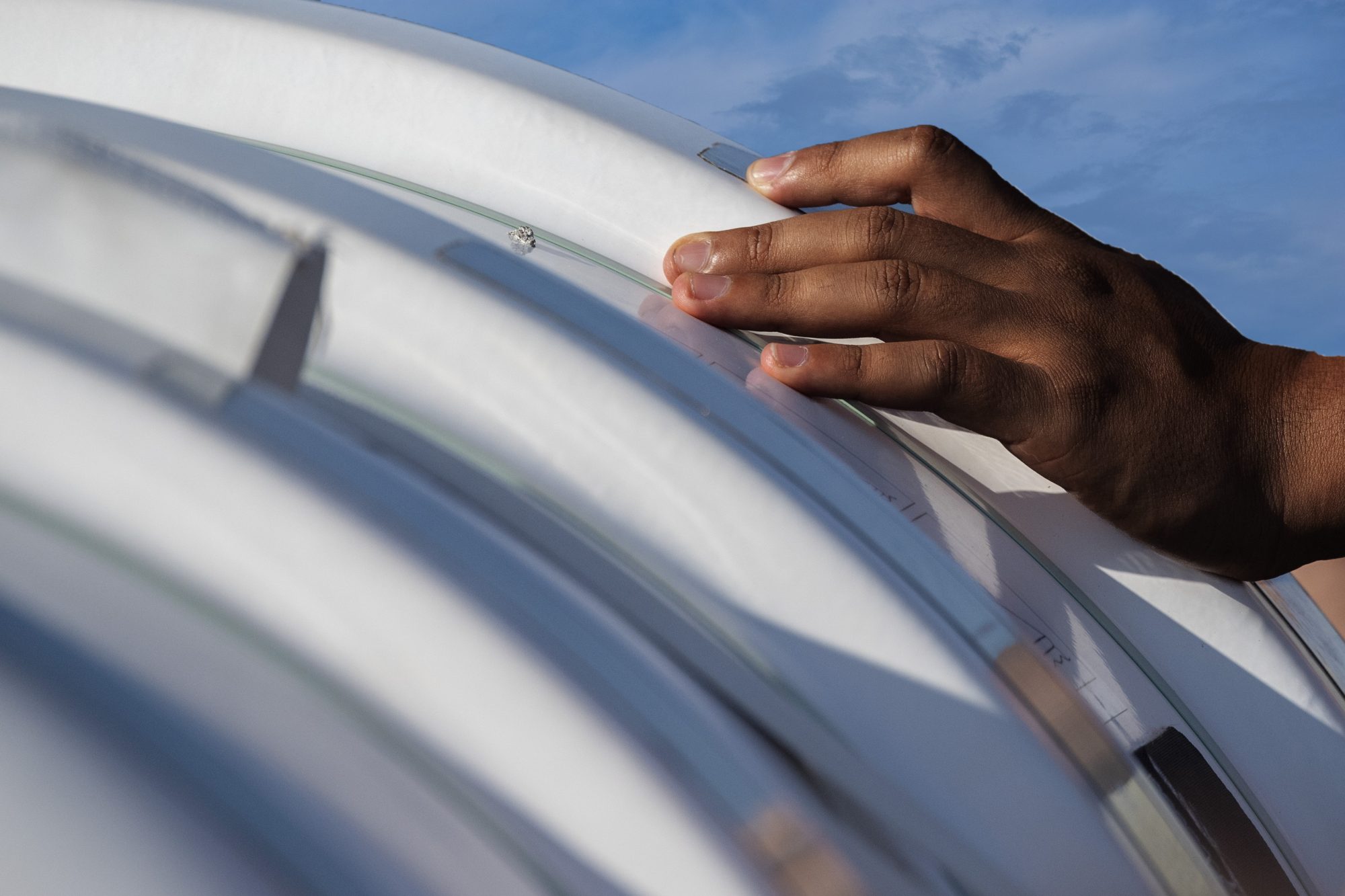 Small, black hand resting on side of boat 