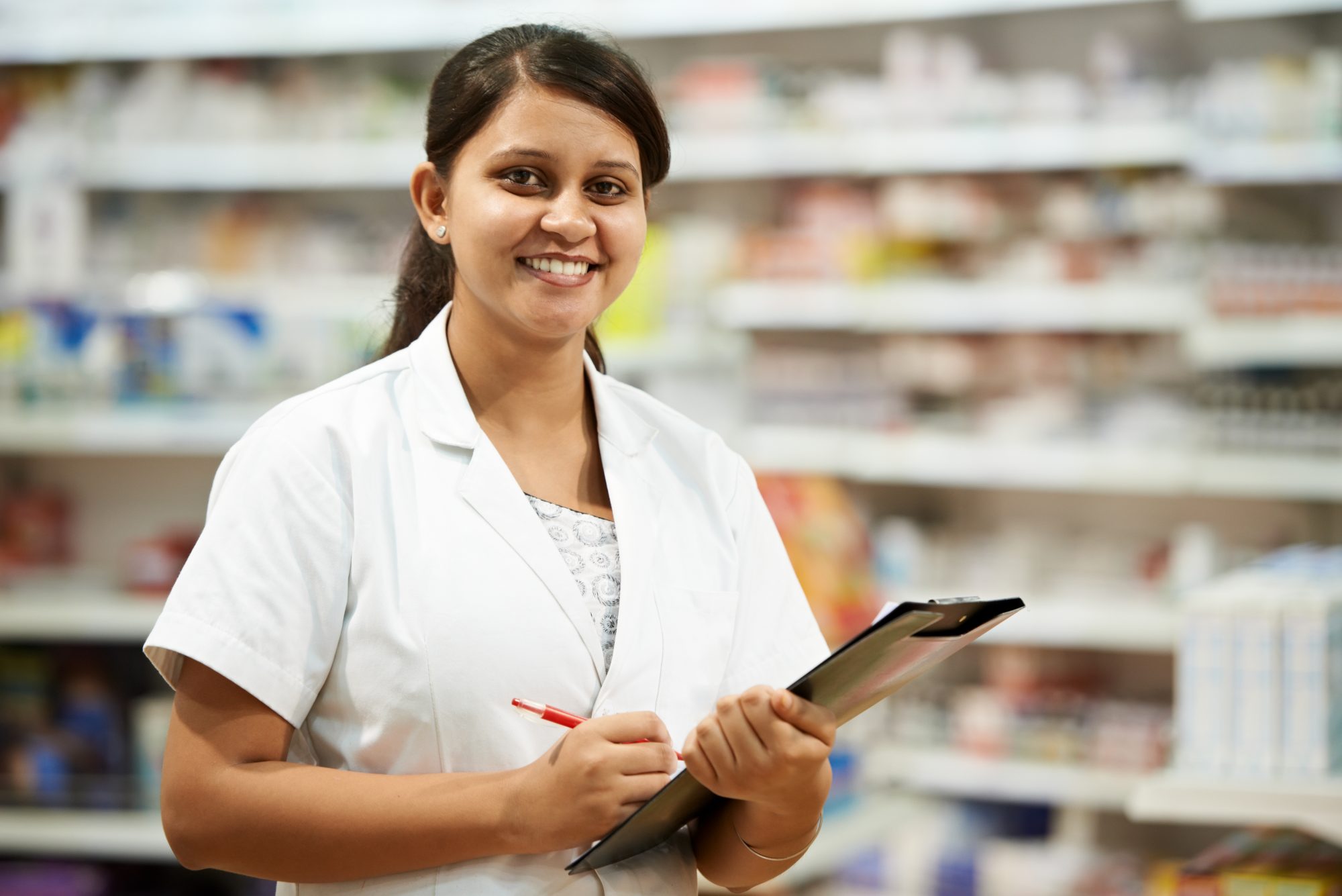 Female pharmacist holding clip board in pharmacy shop