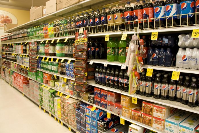 UK supermarket aisle full of shelves of fizzy drinks high in sugar