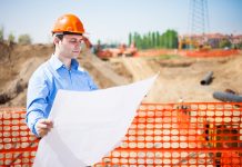 Man in construction hard had looking at plans over building site