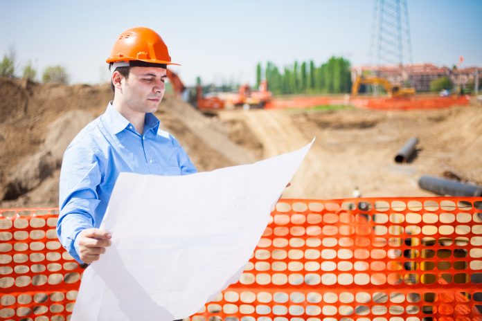 Man in construction hard had looking at plans over building site