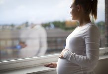 Heavily pregnant woman looking out the window