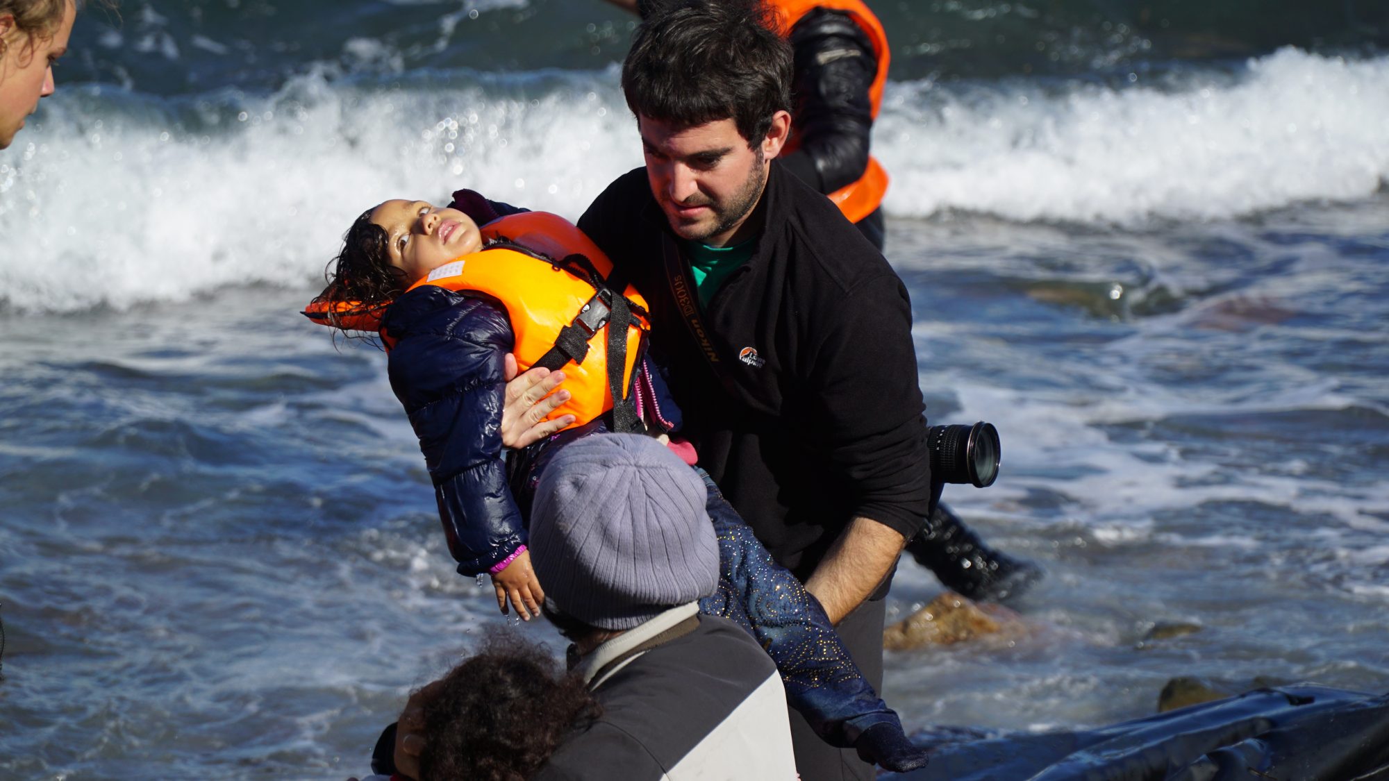 Young boy being pulled from boat after making journey across sea in refugee migrant boat