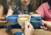 Women holding coffee cups together around table