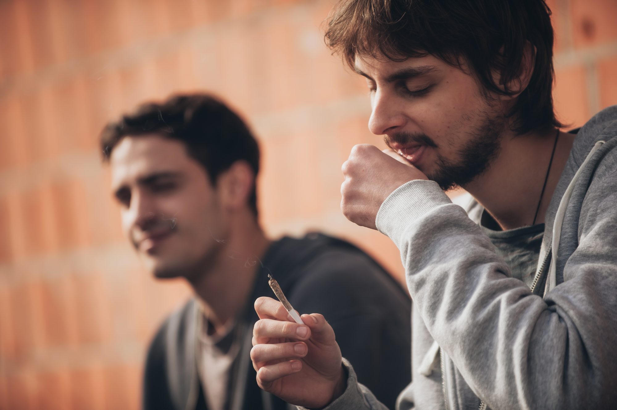 Two young men smiling, happy, smoking weed