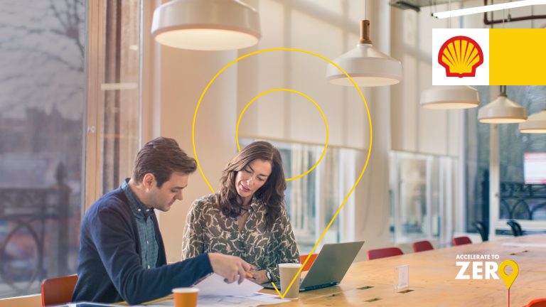 How to reduce operational costs while accelerating decarbonisation of fleets with Sheel Fleet Solutions - two people sat at desk on laptop working at Shell Fleet Solutions discussing strategy