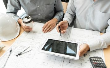 Two engineer and architect discussing blueprints data working and digital tablet